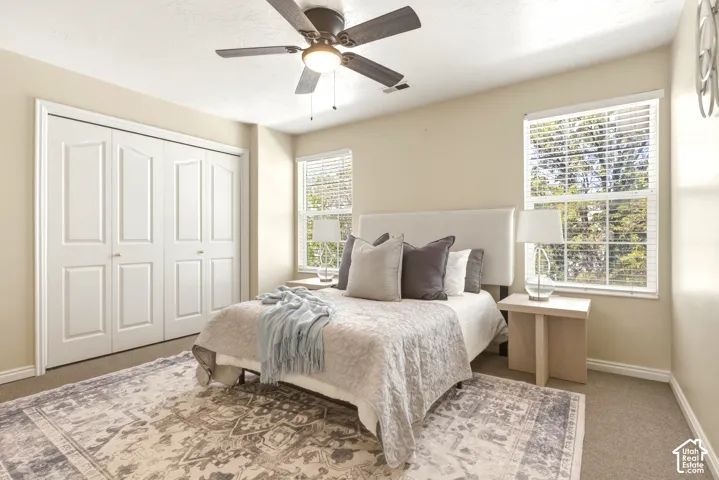 Bedroom featuring a ceiling fan with light fixture, carpeted flooring, and a window with blinds