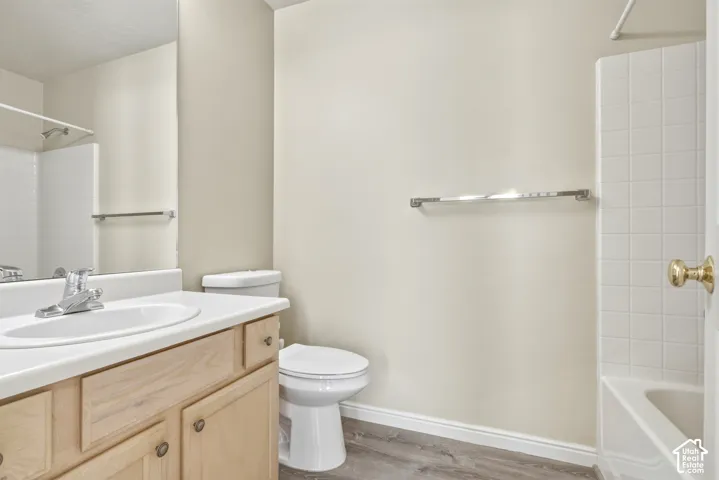 Bathroom featuring a single vanity with a laminate countertop, light wood-finish cabinetry, and a chrome faucet