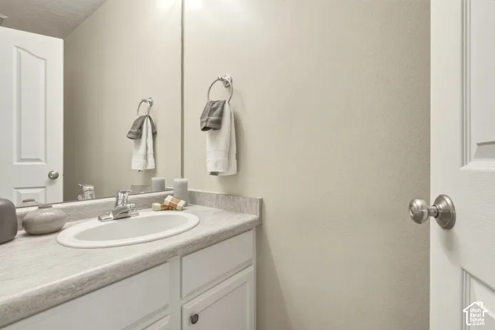 White vanity with an integrated oval sink, chrome faucet, and grey-toned countertop
