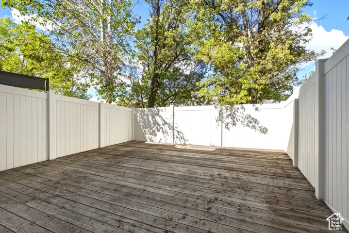 Expansive outdoor deck featuring wood-finish flooring and full privacy fencing