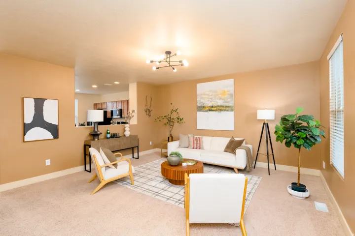 Open-concept living space featuring neutral carpet flooring and warm-toned walls.