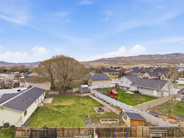 Spacious backyard featuring a manicured lawn, established landscaping, and a white privacy fence