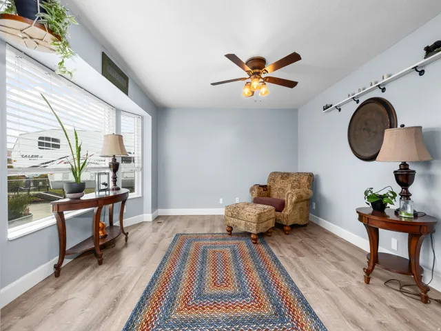 Spacious room featuring light wood-finish flooring, a ceiling fan with integrated lighting, and light blue walls