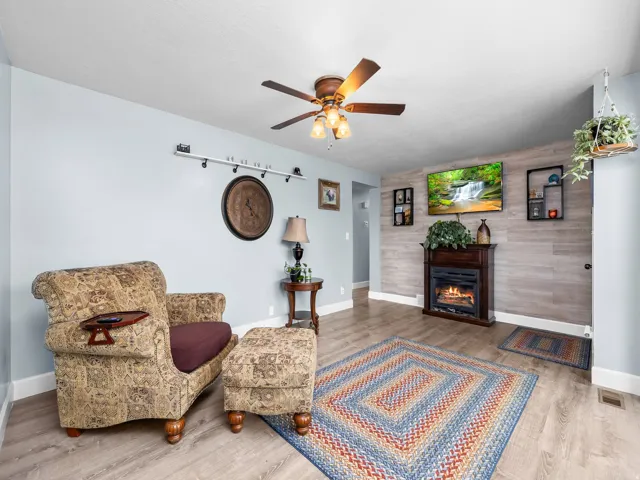 Living area featuring wood-finish flooring and a ceiling fan with integrated lighting
