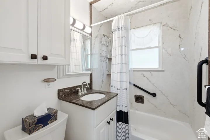 Bathroom with white cabinetry, a dark speckled countertop, and a built-in sink with a chrome faucet