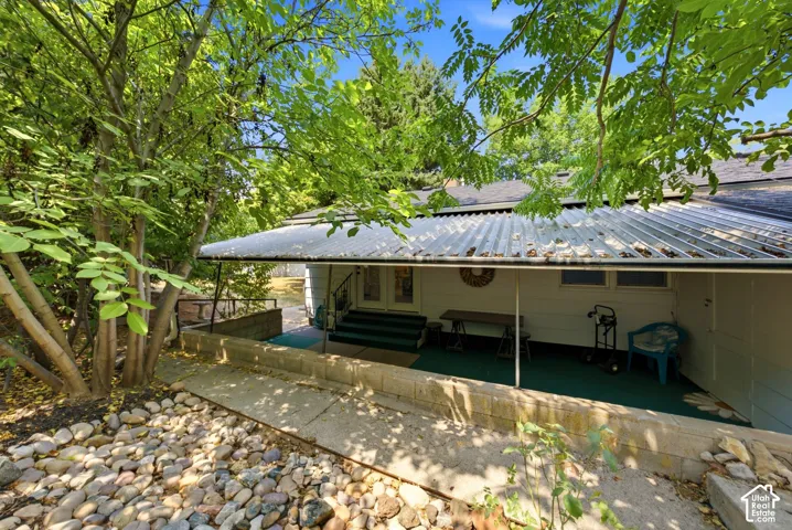 Covered patio area with white siding and a corrugated metal roof