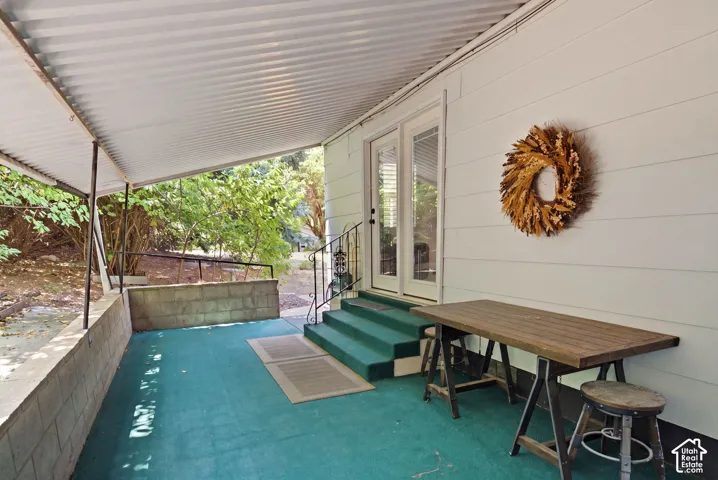 Covered outdoor patio area featuring a corrugated metal roof, painted concrete flooring, and a concrete block retaining wall