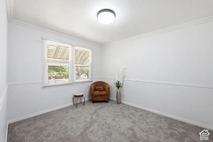 Bright room featuring white walls with wainscoting, crown molding, and a double window with blinds