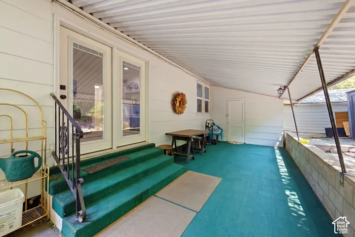 Covered patio area featuring a corrugated metal roof, white siding, and a pair of white-framed glass French doors