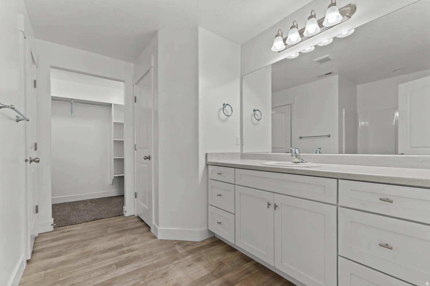 Bathroom featuring a vanity with an integrated sink, light-toned countertop, and white cabinetry
