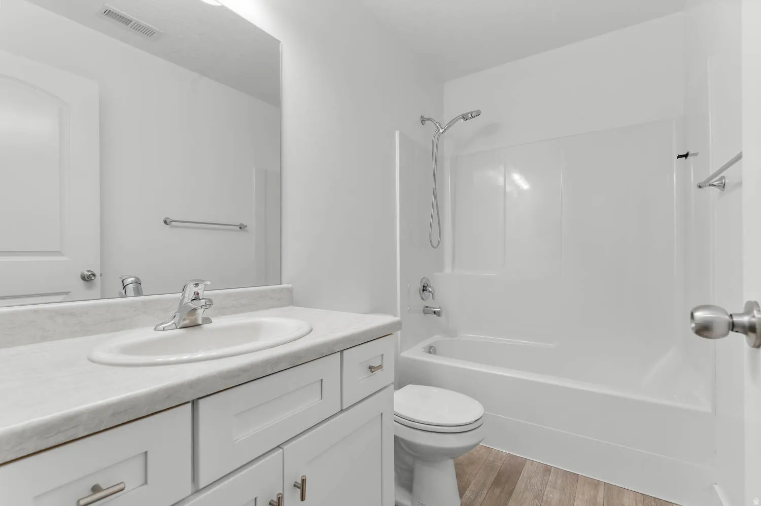 Bathroom featuring a white vanity with an integrated sink, chrome faucet, and a large mirror