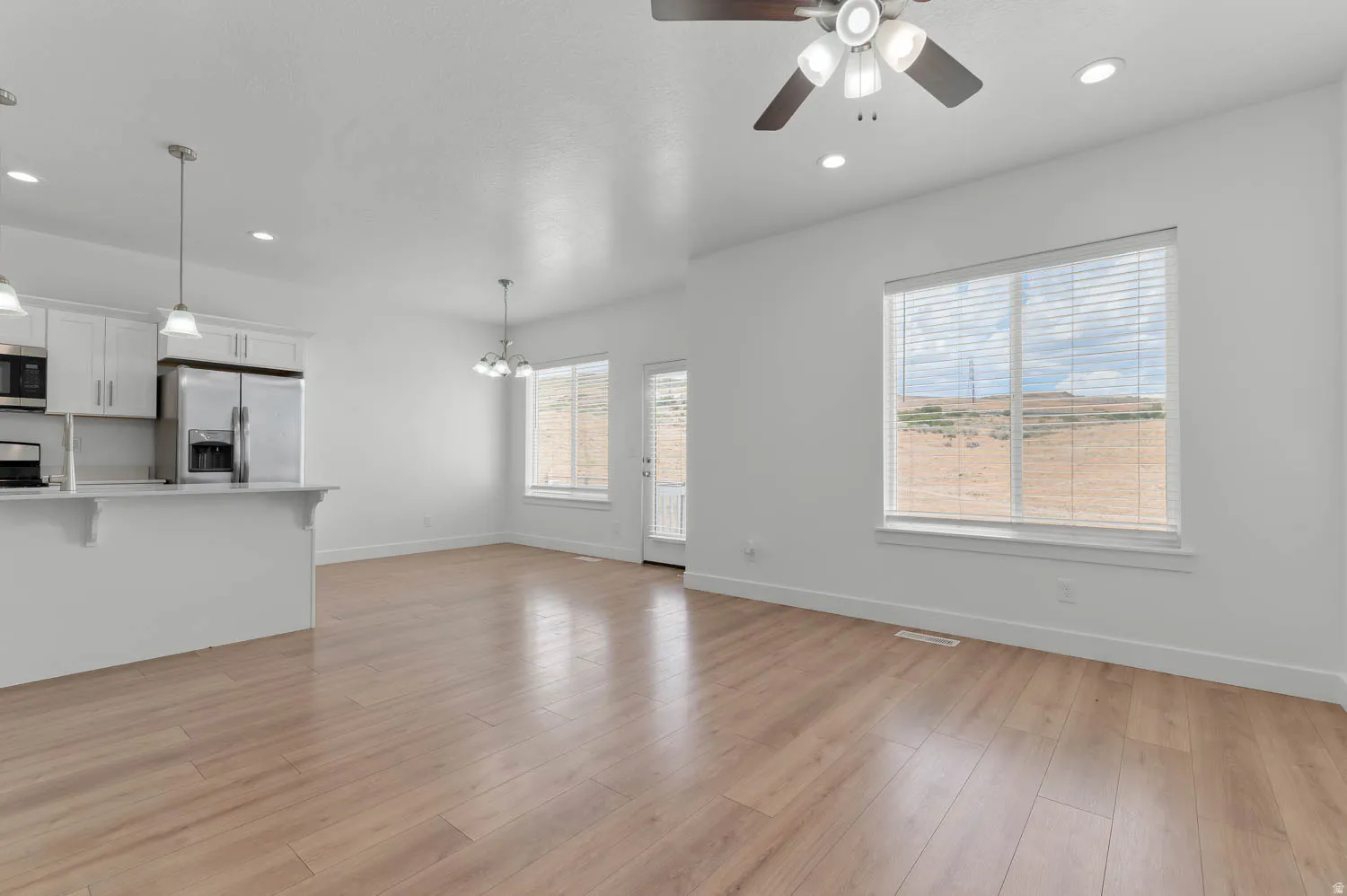 Open-concept living space featuring wood-finish flooring, recessed lighting, a ceiling fan, and white window blinds