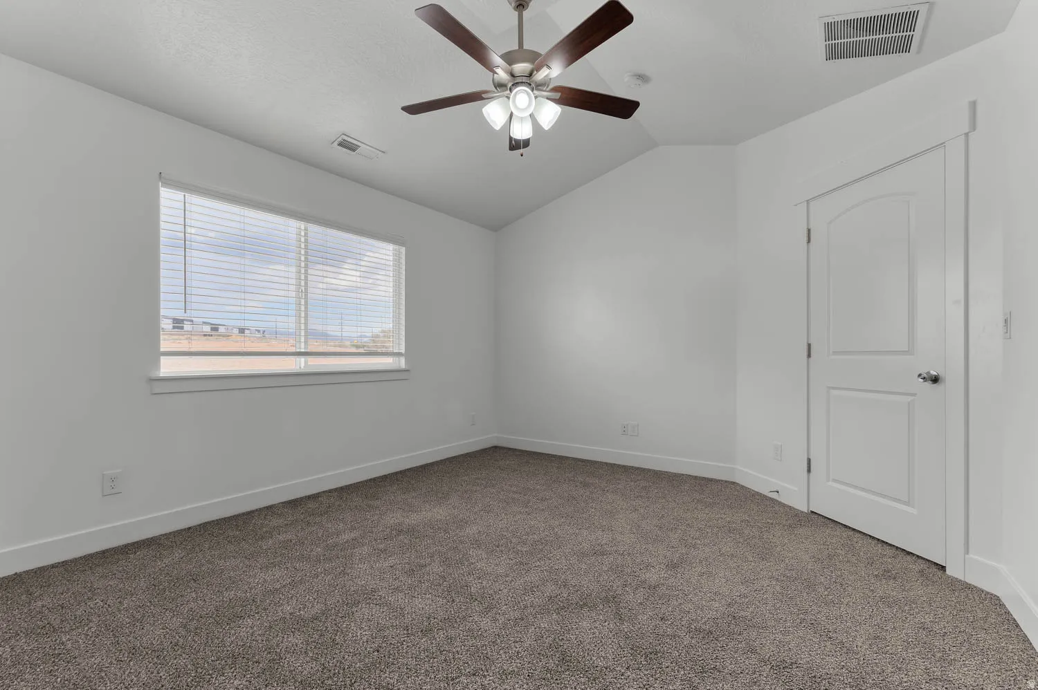 Carpeted room featuring a ceiling fan with light fixture, a window with blinds, and white interior trim