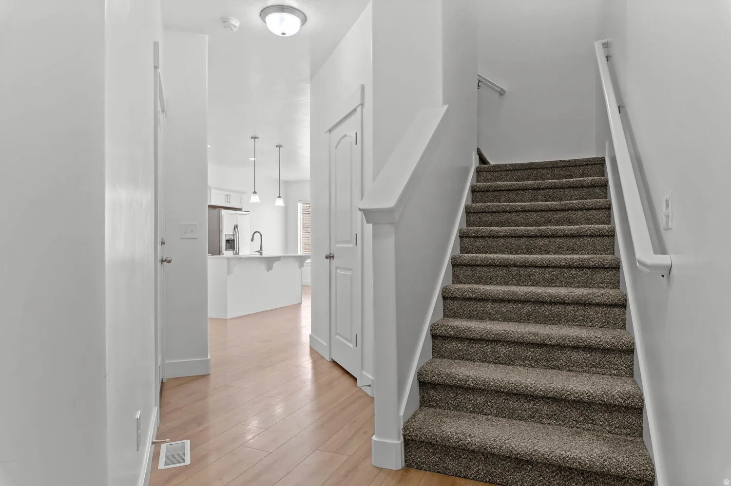 Carpeted staircase with white handrails leading to an upper level