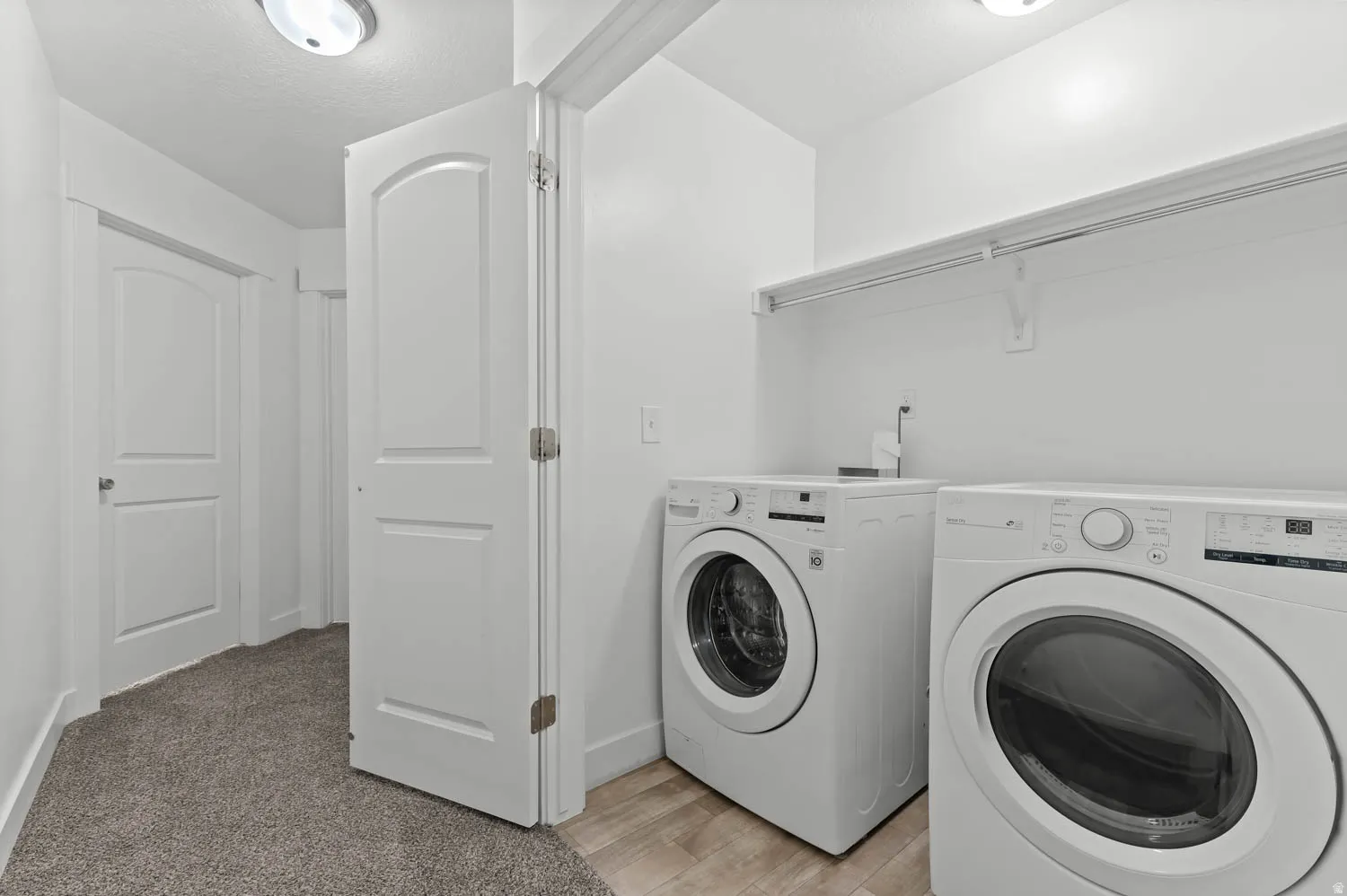 Dedicated laundry area featuring wood-finish flooring, white walls, and a built-in shelving unit