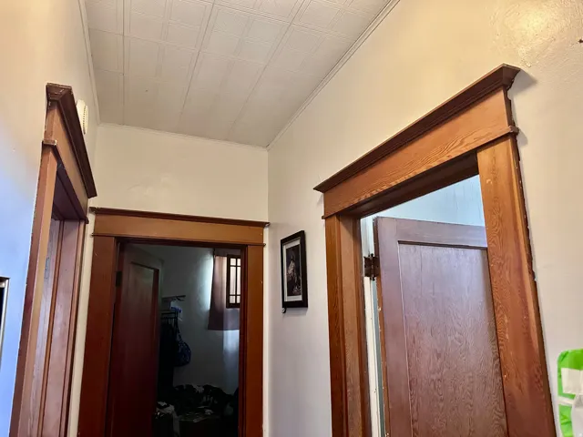 Hallway featuring multiple doorways with wood-finish trim, decorative door casings, and a white ceiling with a subtle patterned texture