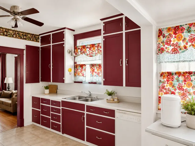 Kitchen featuring extensive cabinetry with red-painted doors, white countertops, a double basin sink, and an integrated dishwasher