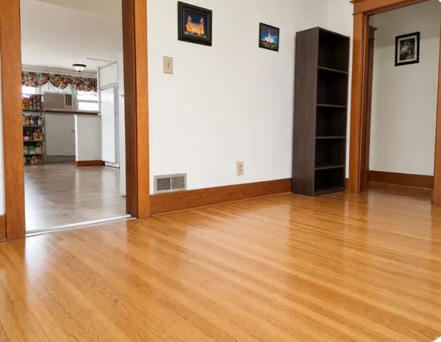 Hardwood flooring, painted walls, wood trim, and a tile-floored kitchen