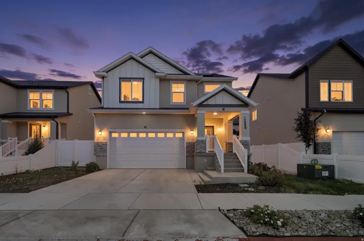 Contemporary two-story residence featuring a two-car garage, stone facade accents, and a covered porch entry