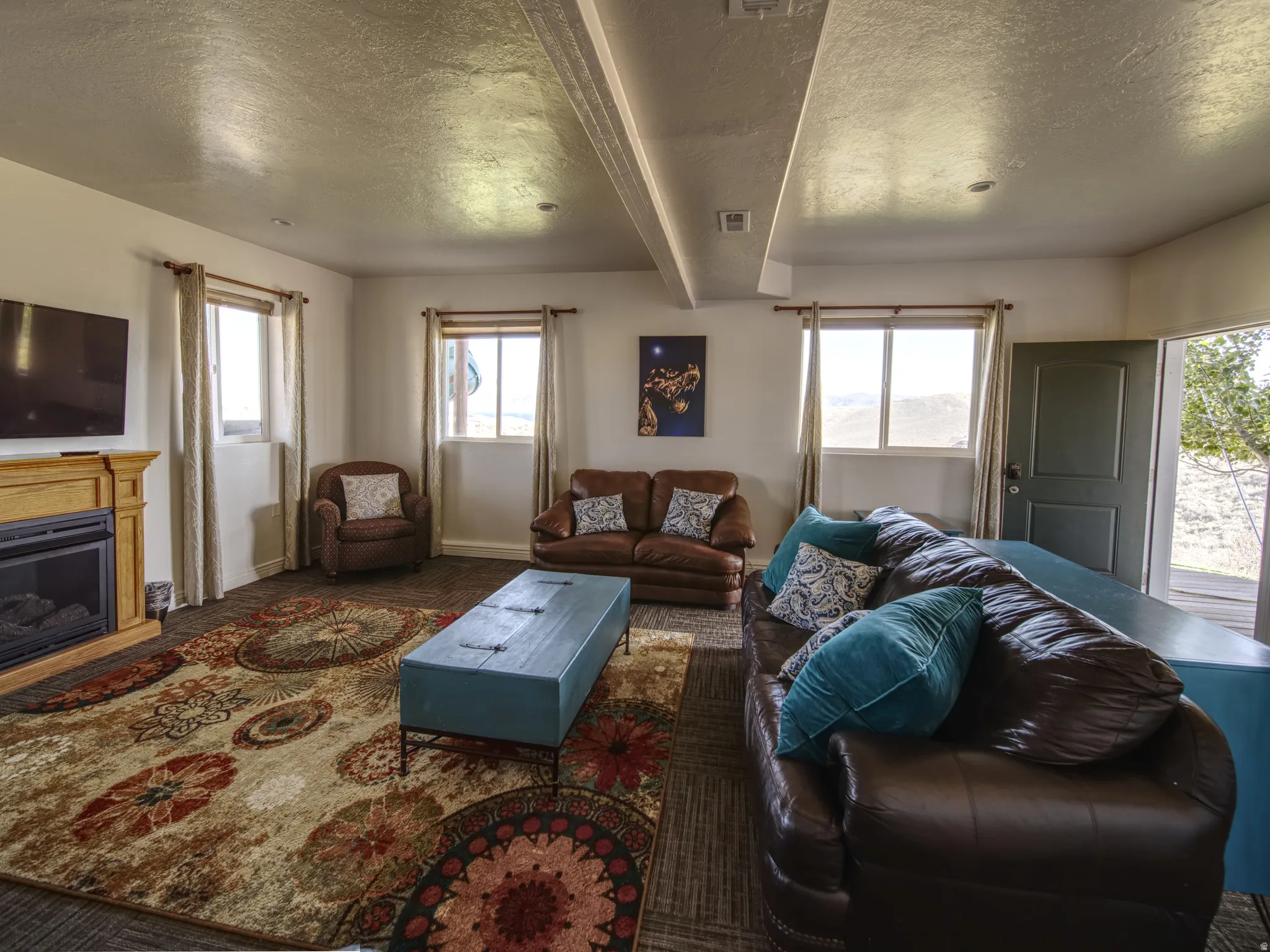 Spacious interior room featuring multiple windows, a light wood-finish fireplace, and an exterior door