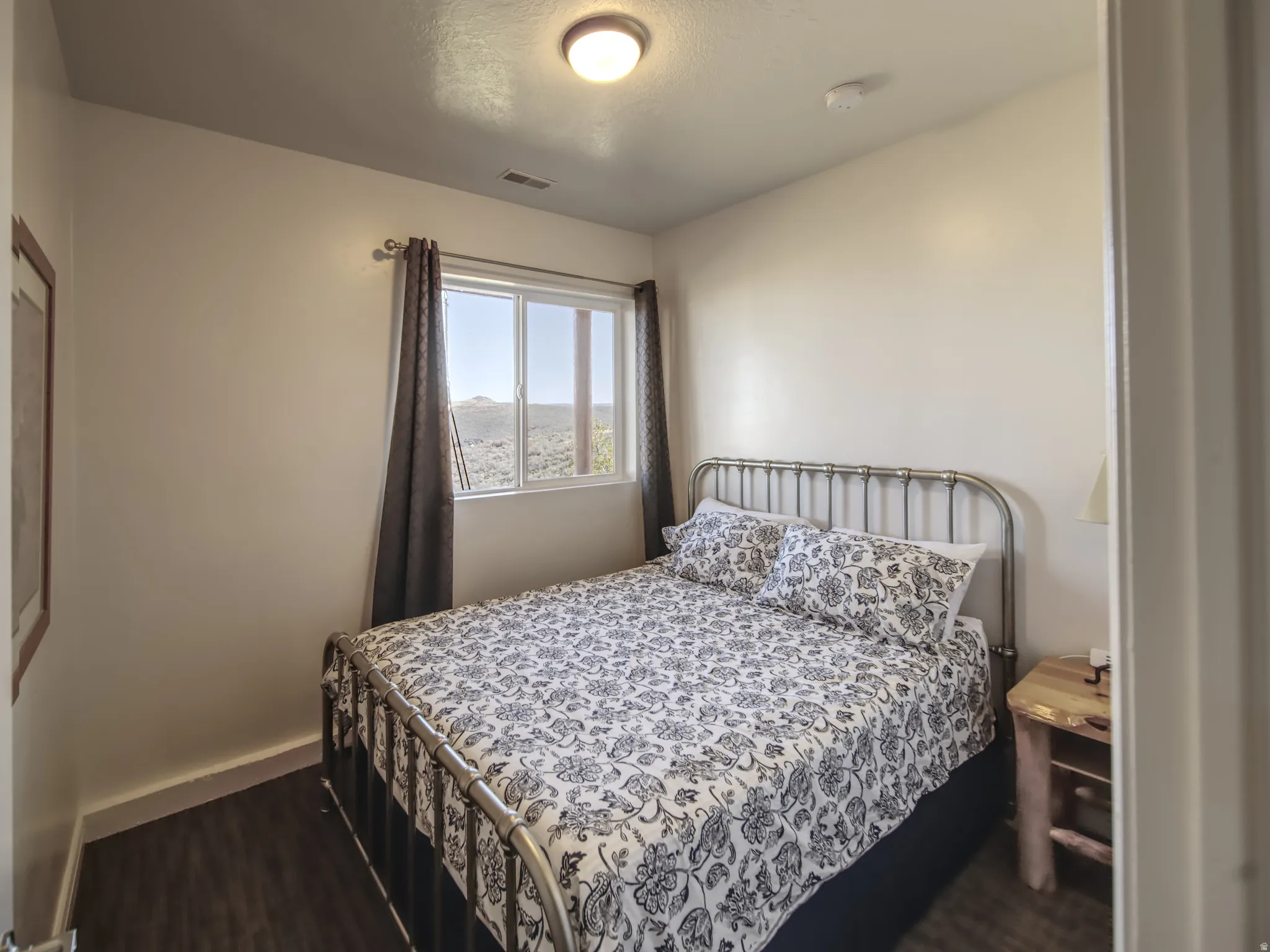 Bedroom featuring a multi-pane window, wood-finish flooring, and a metal bed frame