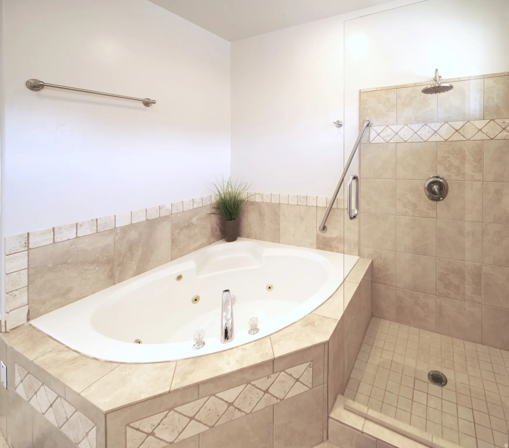 Corner jetted tub with tiled surround featuring decorative accents