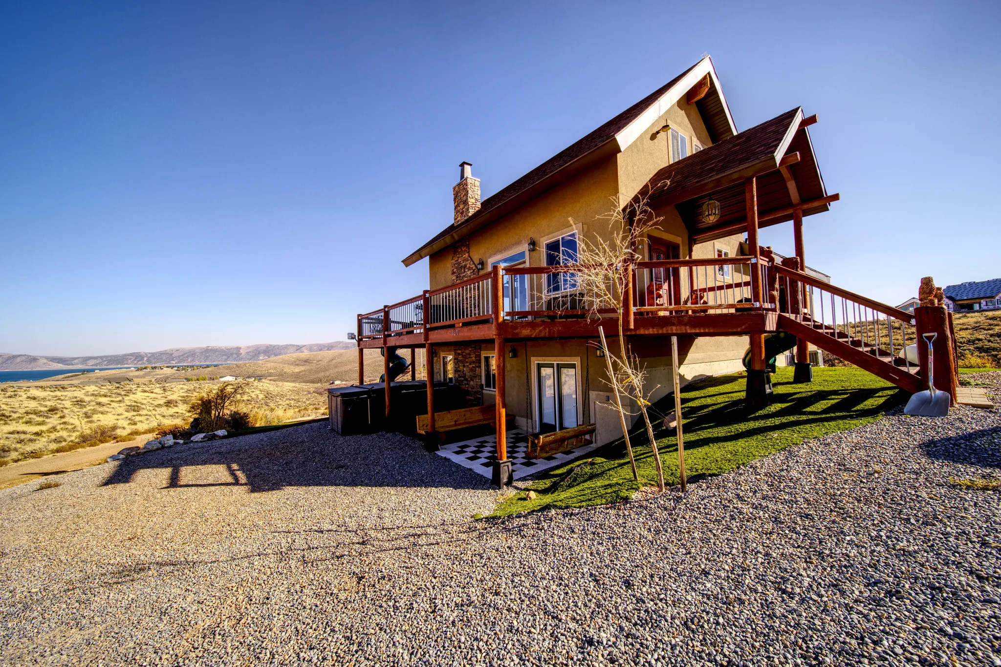 Multi-level structure featuring a stone chimney, extensive wood decking, and a covered entry porch