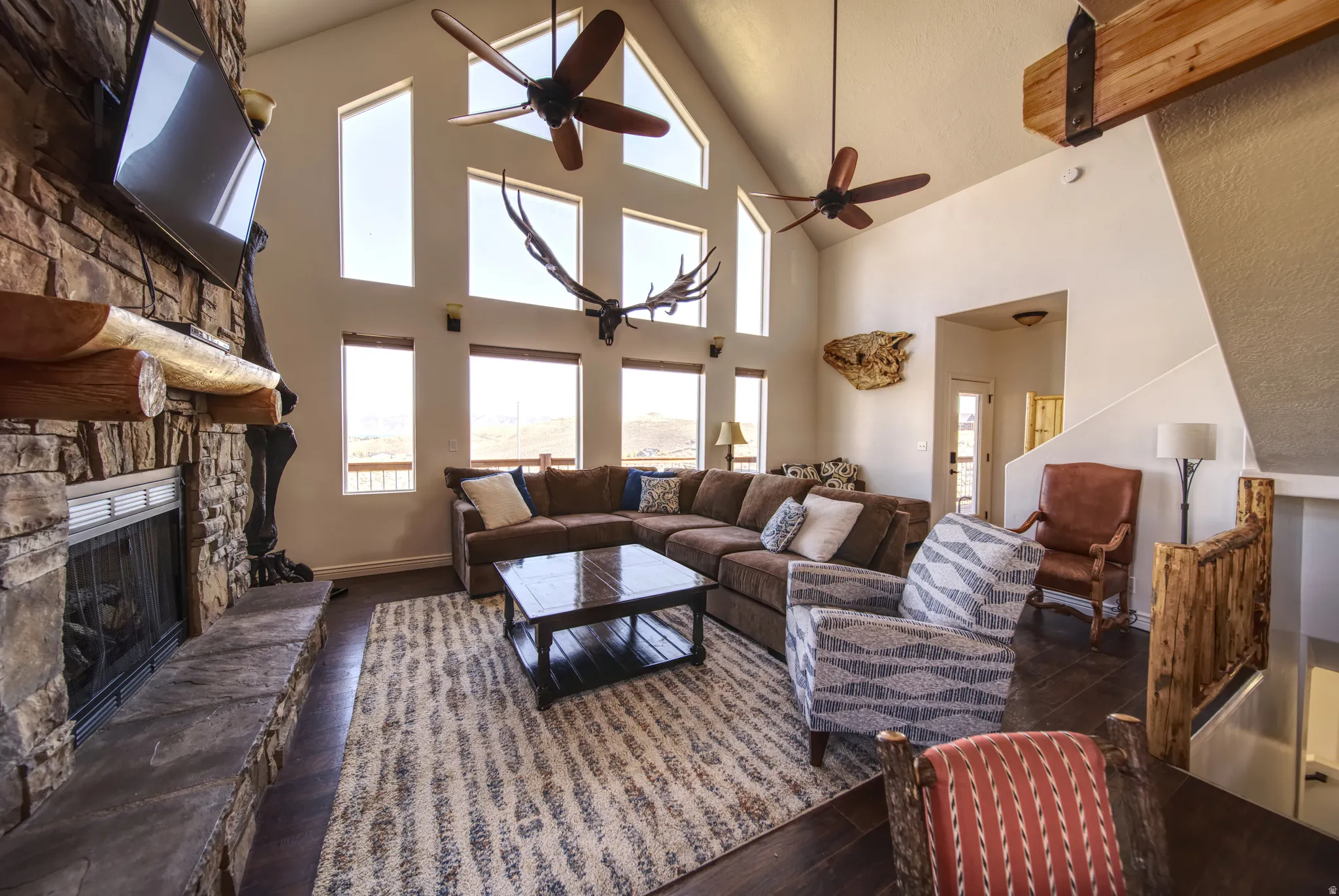 Vaulted living room with a prominent stone-clad fireplace and hearth, showcasing a substantial wood mantel