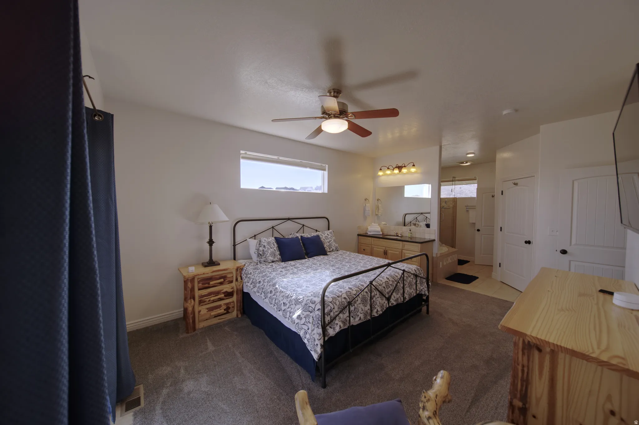 Spacious room featuring a ceiling fan, dual vanity with undermount sinks, and a walk-in shower