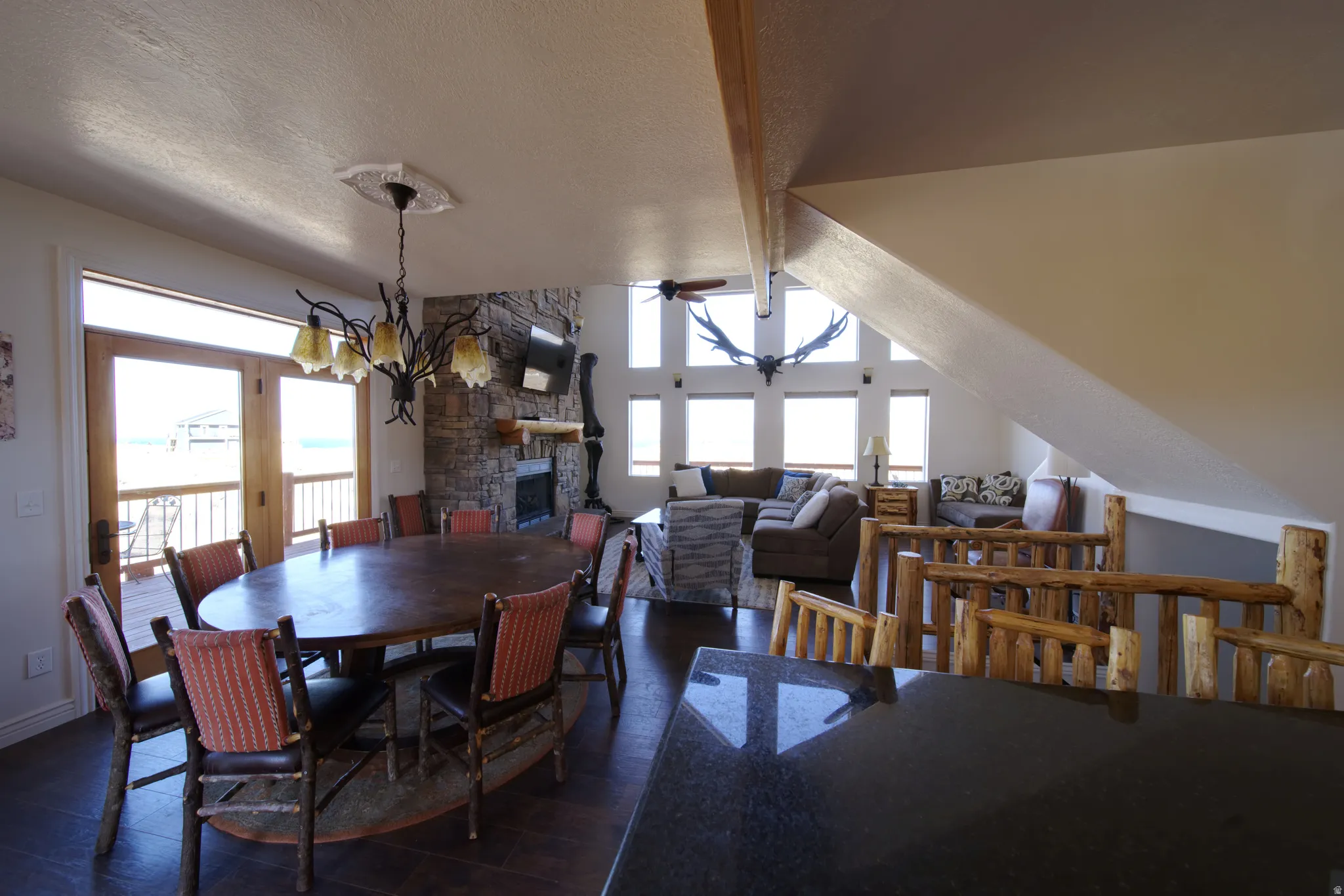 Open-concept living space with a stone fireplace, vaulted ceilings, and large windows