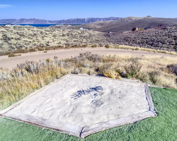 Open land parcel with natural landscaping, featuring a flat sand area with an artistic imprint