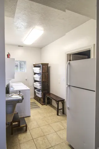 Utility room with neutral-toned tile flooring, white walls, and a fluorescent ceiling light fixture