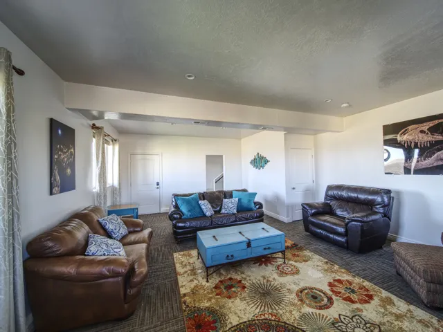 Spacious room featuring neutral wall tones, recessed lighting, and a textured carpeted floor