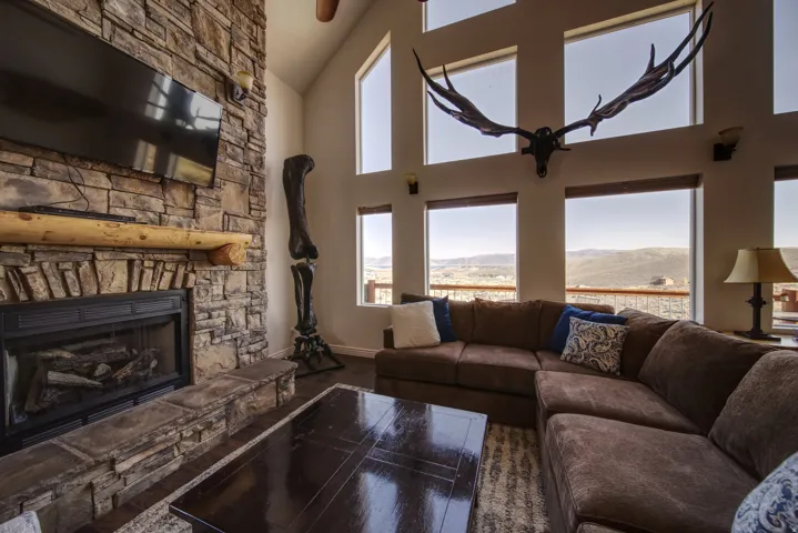 Vaulted ceilings highlight a stone fireplace featuring a log mantel