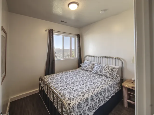 Bedroom featuring a multi-pane window, wood-finish flooring, and a metal bed frame