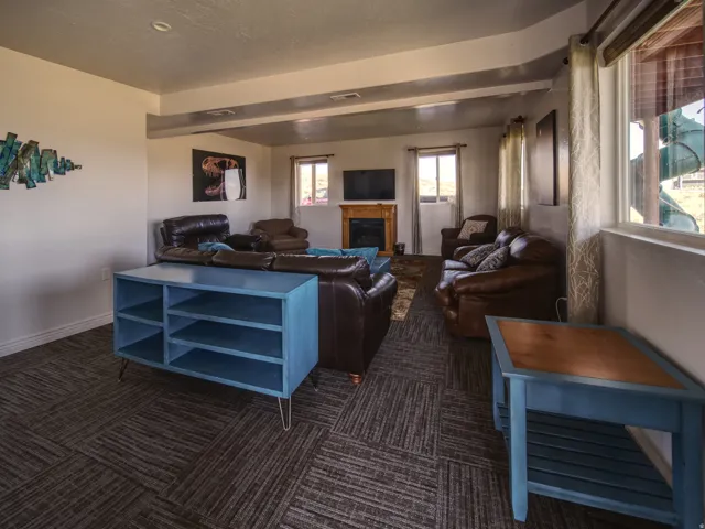 Spacious living area featuring patterned carpet flooring, multiple windows, a built-in fireplace with a wood-finish mantel, and recessed lighting