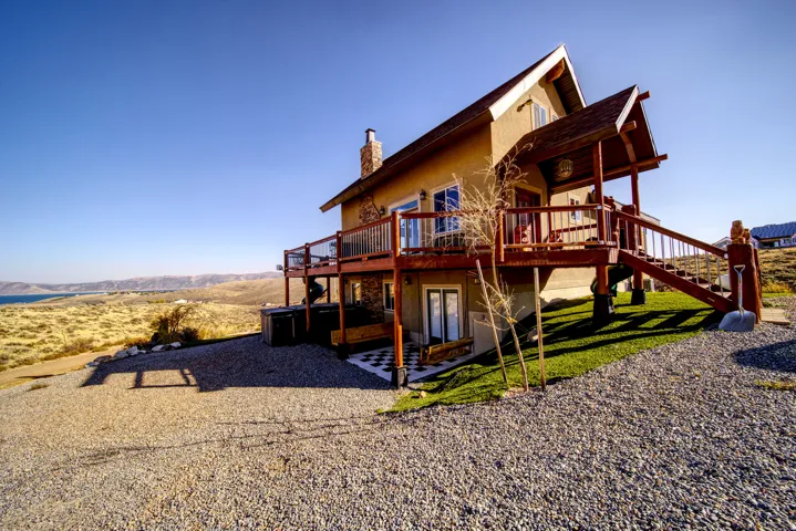 Multi-level structure featuring a stone chimney, extensive wood decking, and a covered entry porch