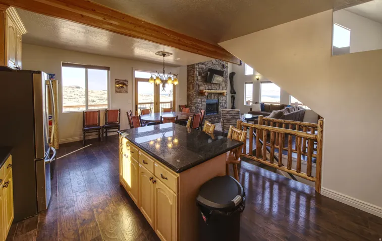 Kitchen and dining area featuring wood-finish flooring, light cabinetry, and a central island with a dark countertop