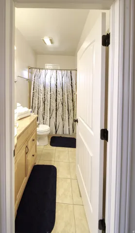 Full bathroom featuring a single vanity with wood cabinetry and a light-colored countertop, tiled flooring, and a shower/tub combination with a window