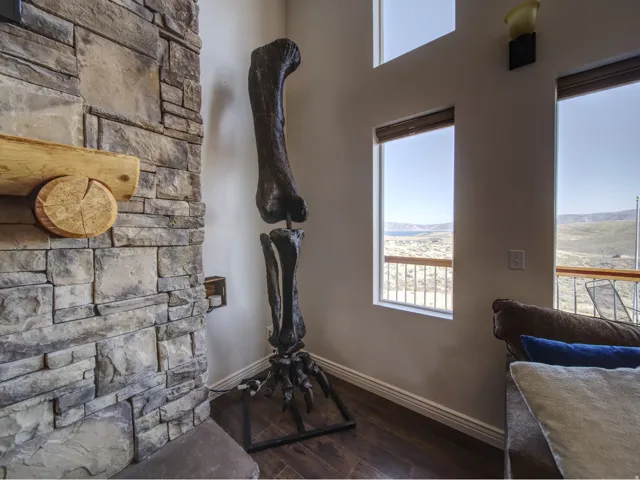 Stacked stone fireplace with a rustic wood mantel, complemented by wood-finish flooring