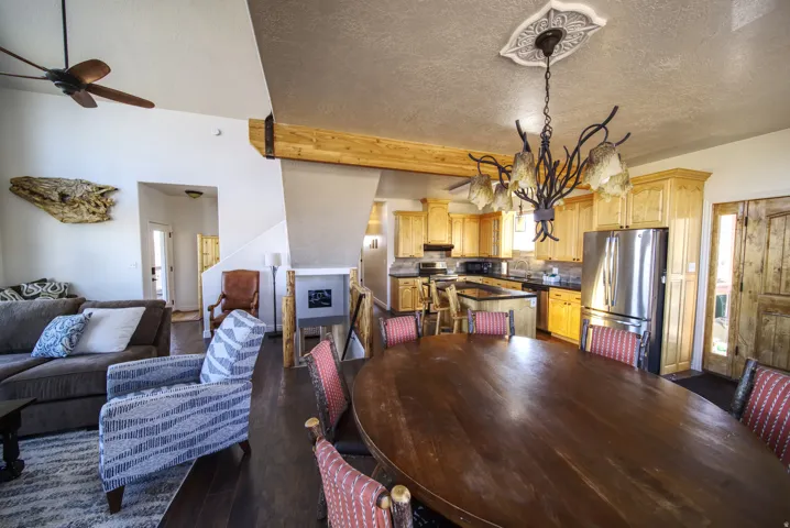 Open-concept living space featuring wood-finish flooring, a decorative ceiling medallion with a chandelier, and a prominent wood beam detail
