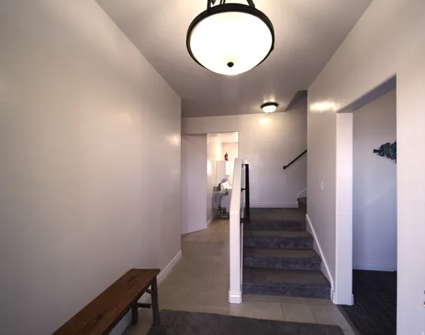 Entryway featuring tile flooring, a carpeted staircase with a dark handrail, and recessed lighting