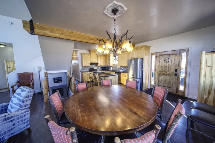 Open-concept living area with a large wood-finish dining table and rustic chandelier