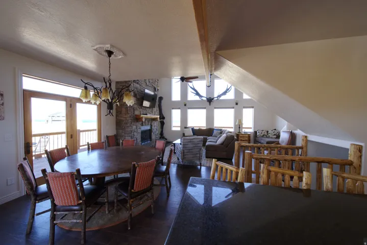 Open-concept living space with a stone fireplace, vaulted ceilings, and large windows