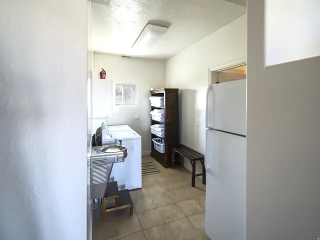 Dedicated utility room featuring light tile flooring, a window, and a fluorescent ceiling light fixture