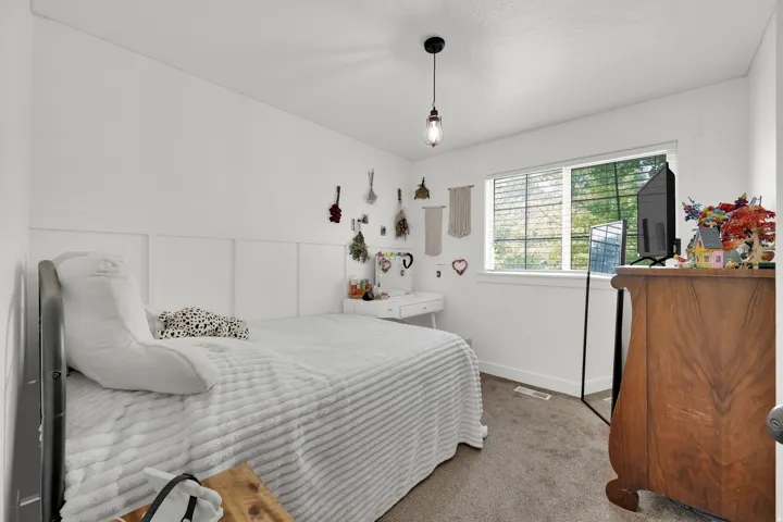 Bright interior space featuring a window with integrated blinds, a white board and batten accent wall, and neutral carpeting