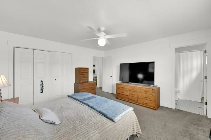 Carpeted sleeping area with white walls and a ceiling fan