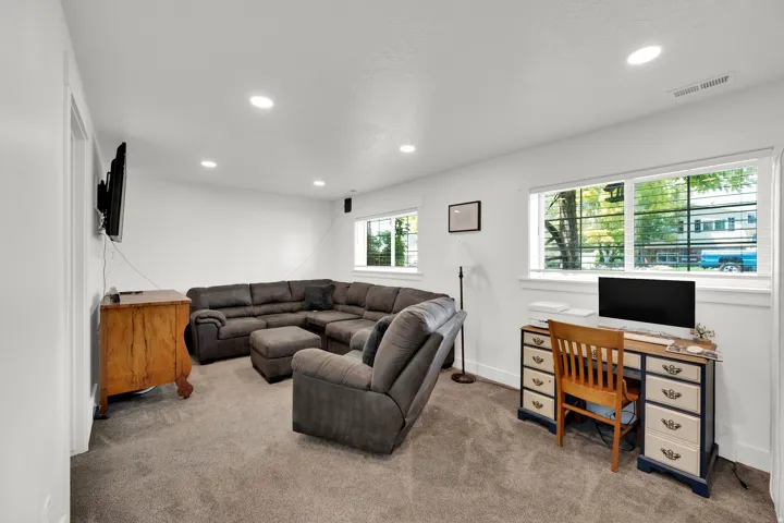 Spacious interior room featuring light gray carpeting, white painted walls, and recessed lighting