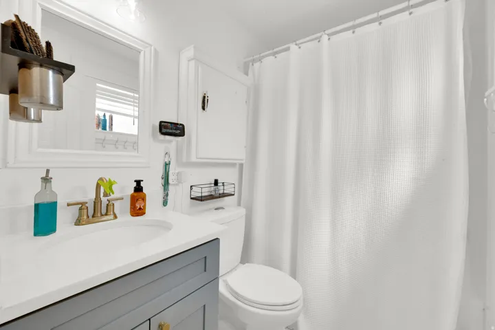 Bathroom featuring a white countertop, gray vanity cabinetry, and a white framed mirror
