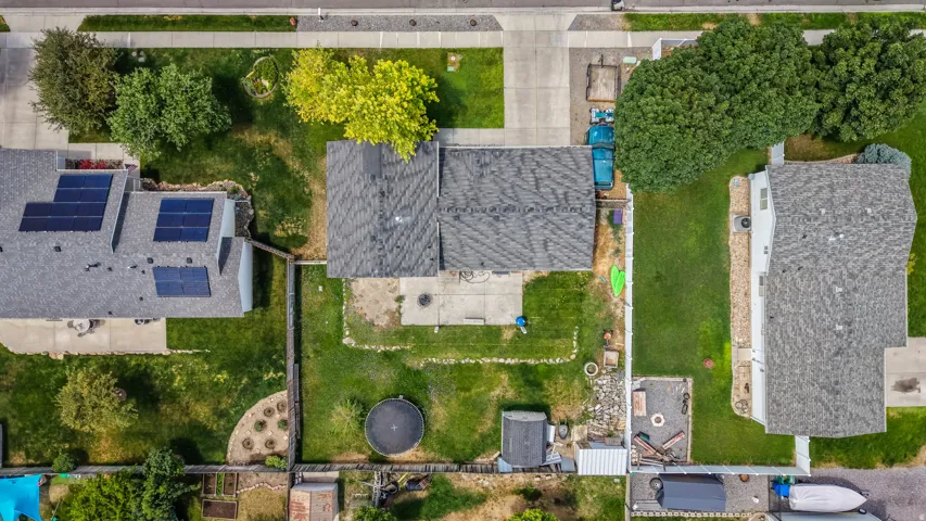 Spacious backyard featuring a substantial patio area, mature trees providing natural shade, and a manicured lawn